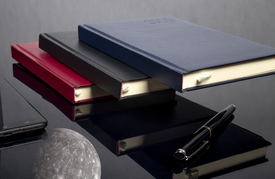 Kalendarze OPUS O.DIARY Merkury leżące na sobie na biurku obok smartfona i długopisu - aranżacja